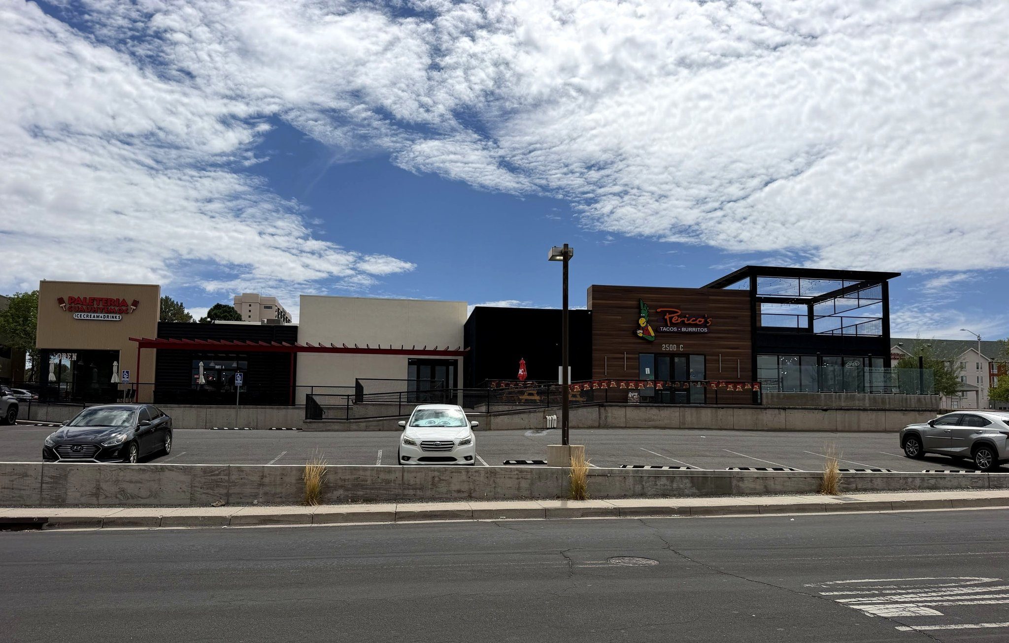 Yale Landing seen from Yale Blvd SE — Paleteria Cuauhtemoc, the vacant Suite B frontage, and Perico's Burritos · Tacos with the upstairs taproom.