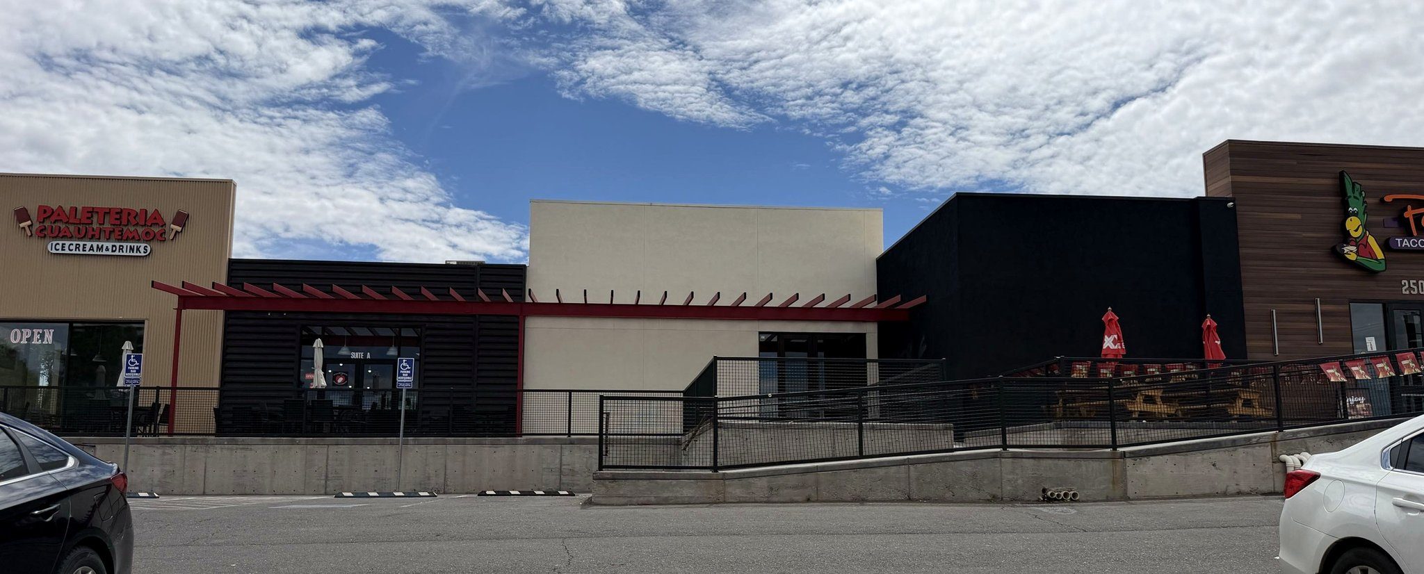 The Yale Landing frontage from the parking lot — Paleteria Cuauhtemoc at one end, Perico's at the other, and the available inline retail bay between them.
