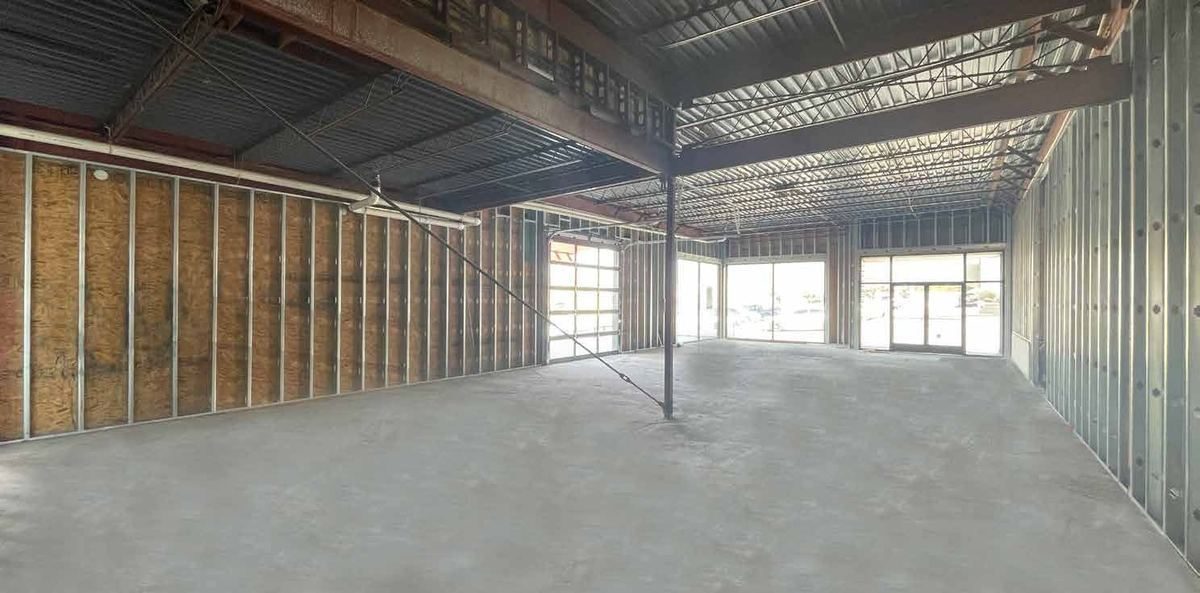 Open shell interior of Suite B with storefront glazing and concrete floors.
